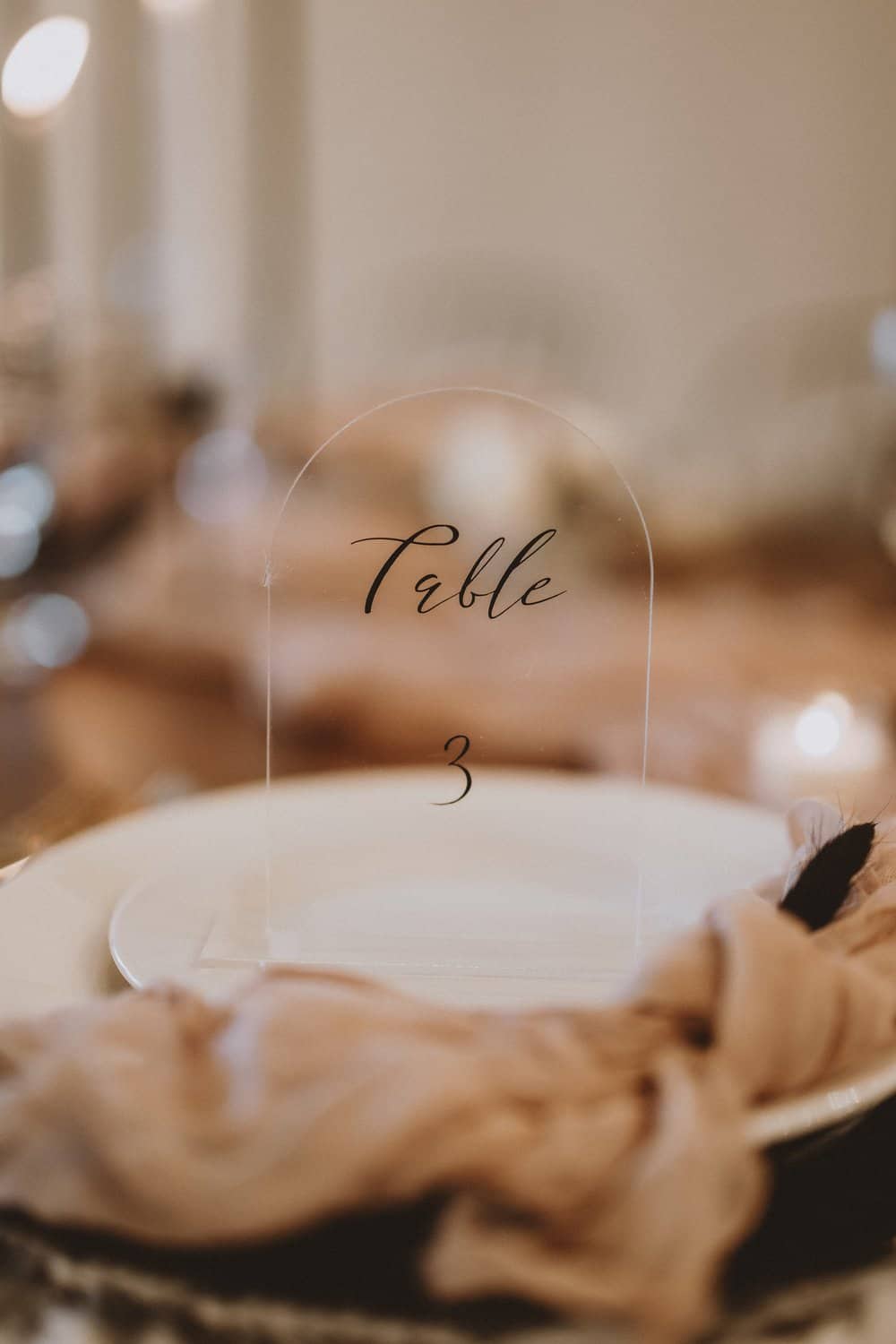 Table setting with a "Table 3" sign on a white plate, decorated with a soft fabric.